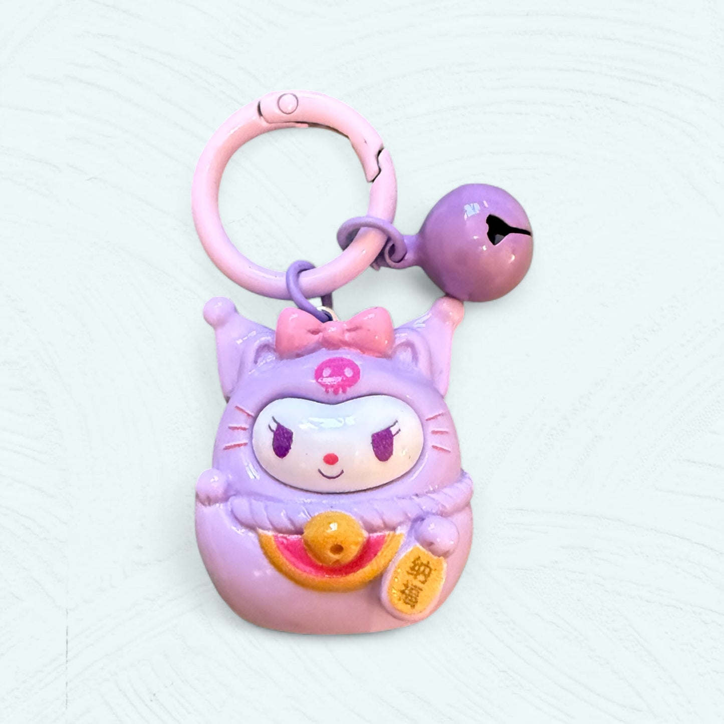 Porte-clés Daruma Kuromi, en violet foncé avec son chapeau d’arlequin et une expression espiègle.