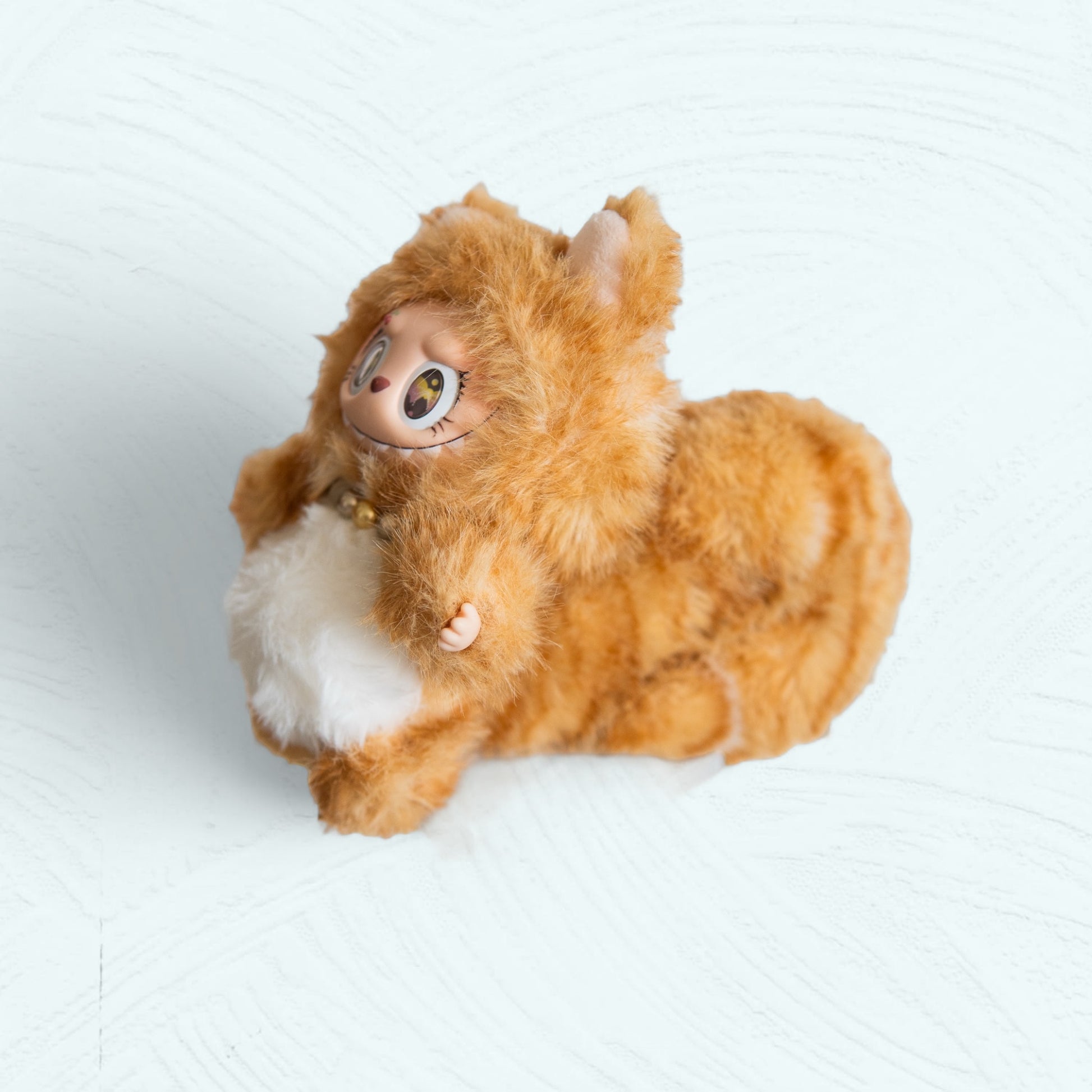 Vue de profil de la figurine Labubu en chat roux montrant la queue et le maquillage latéral.