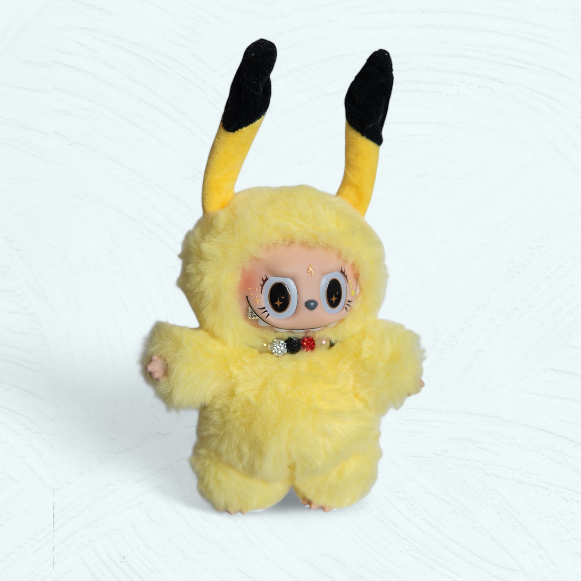 Face de la poupée Labubu déguisée en Pikachu, costume jaune avec oreilles noires