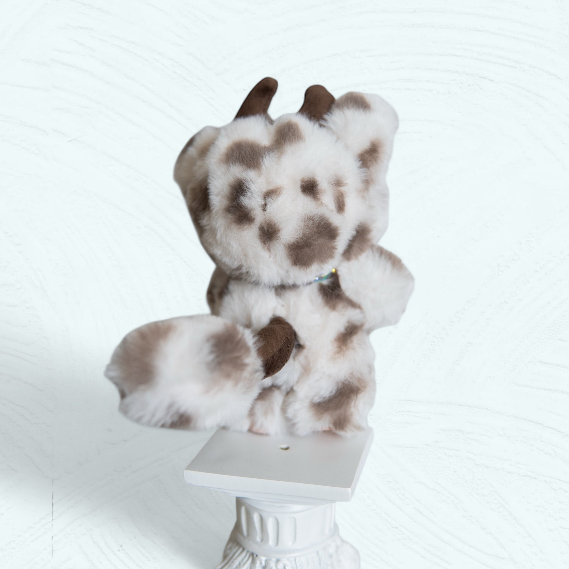 Vue arrière du Labubu costumisé en vache, montrant les détails de la fourrure et de la queue.