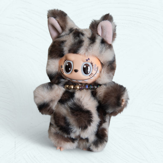 Labubu en costume de léopard vu de face, peluche tachetée et collier de perles.