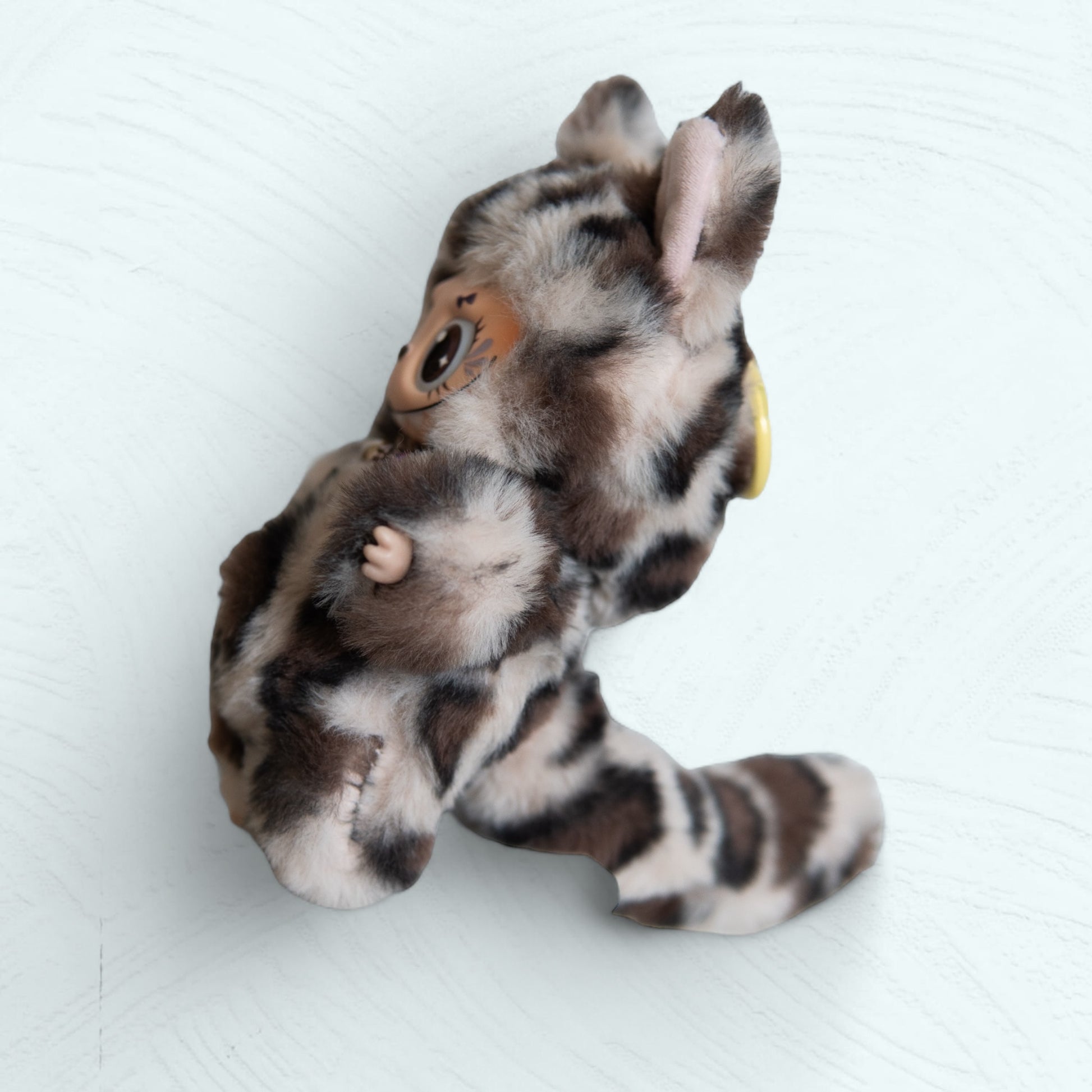 Vue latérale de la figurine Labubu léopard, avec sa longue queue.