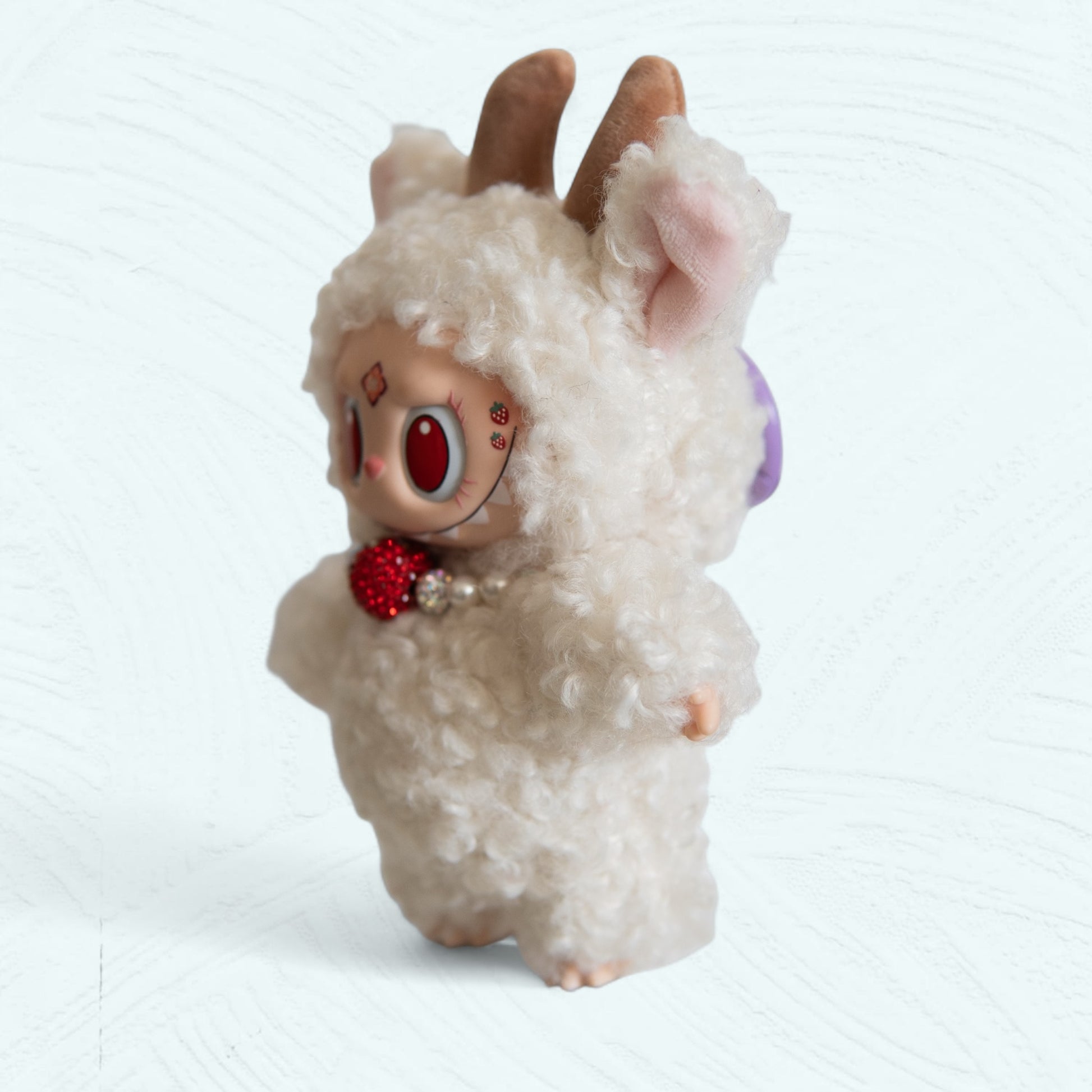 Vue latérale du Labubu mouton montrant les oreilles et les détails bouclés.