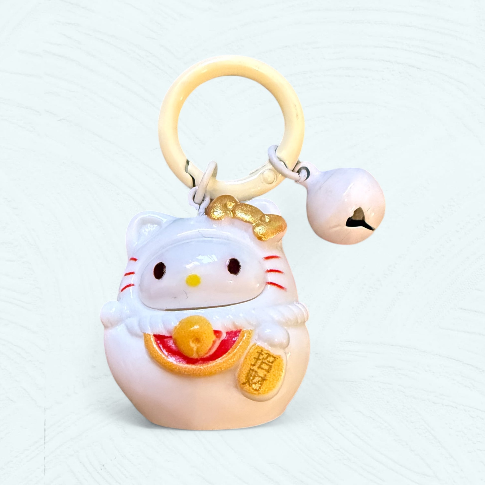 Porte-clés Daruma Hello Kitty, en rouge et blanc avec un nœud sur la tête et un visage de style japonais.