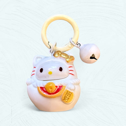 Porte-clés Daruma Hello Kitty, en rouge et blanc avec un nœud sur la tête et un visage de style japonais.
