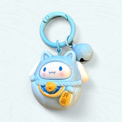 Porte-clés Daruma Cinnamoroll, en bleu clair avec de grandes oreilles repliées et un visage souriant.