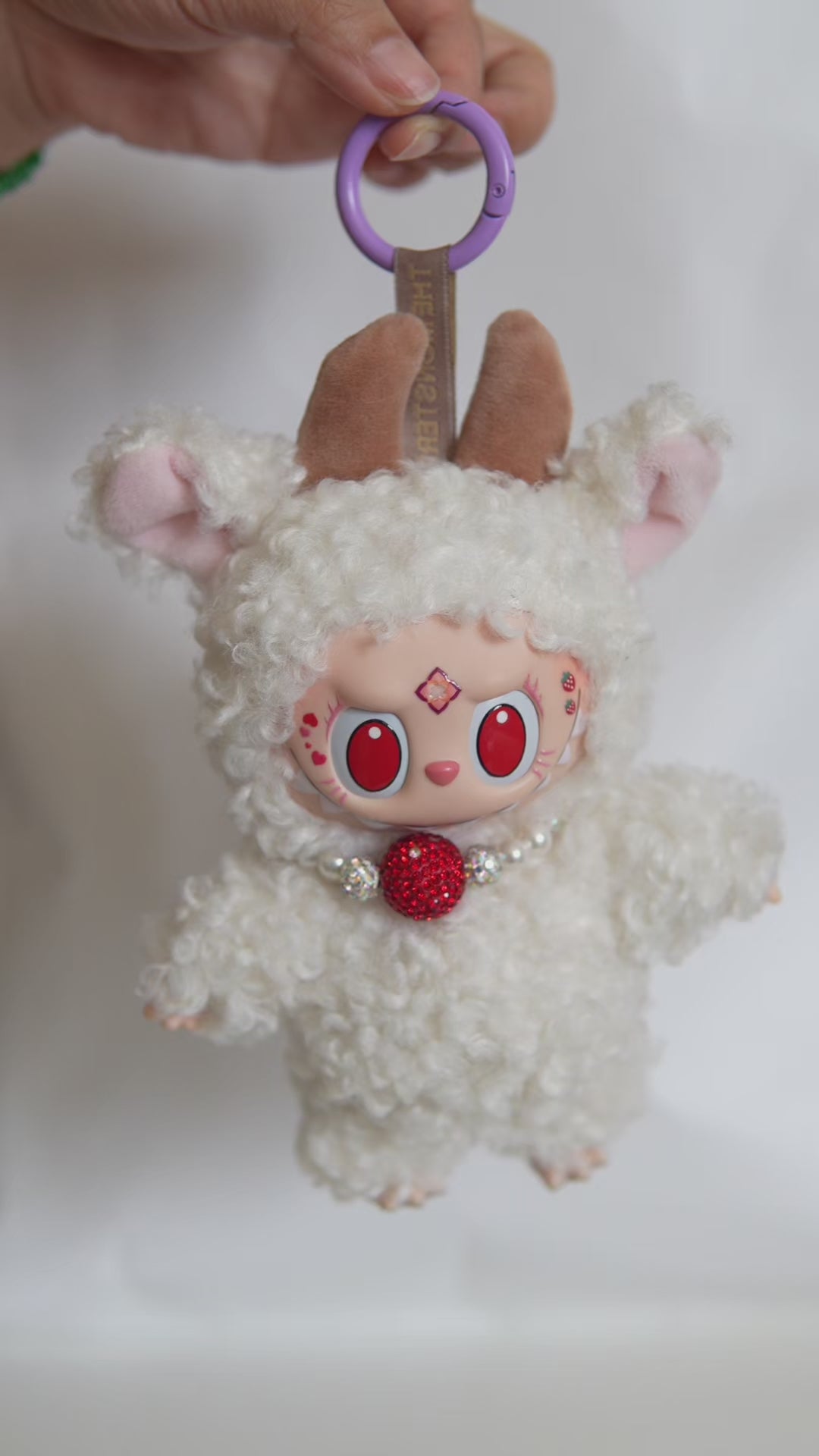 Vidéo du Labubu customisé en mouton : tenue bouclée, collier perlé et cornes en velours.